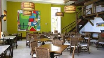 A dining area with tables and chairs, a staircase, and a colorful abstract painting on the wall.