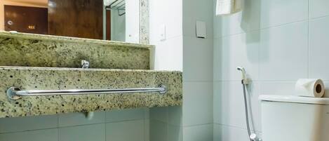 A bathroom with a toilet, a towel rack, a mirror, and a shower area.