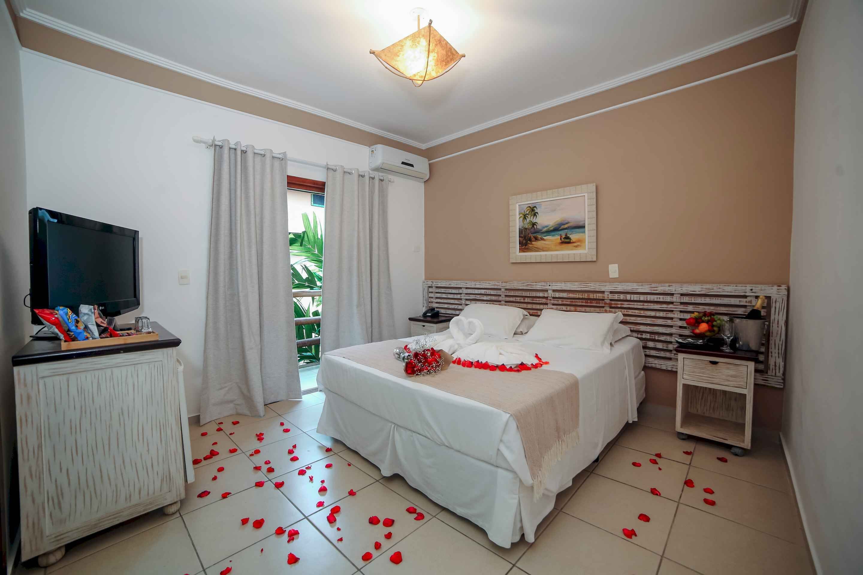 Ein Hotelzimmer mit Bett, Fernseher, Nachttisch und Fenster mit Vorhängen.