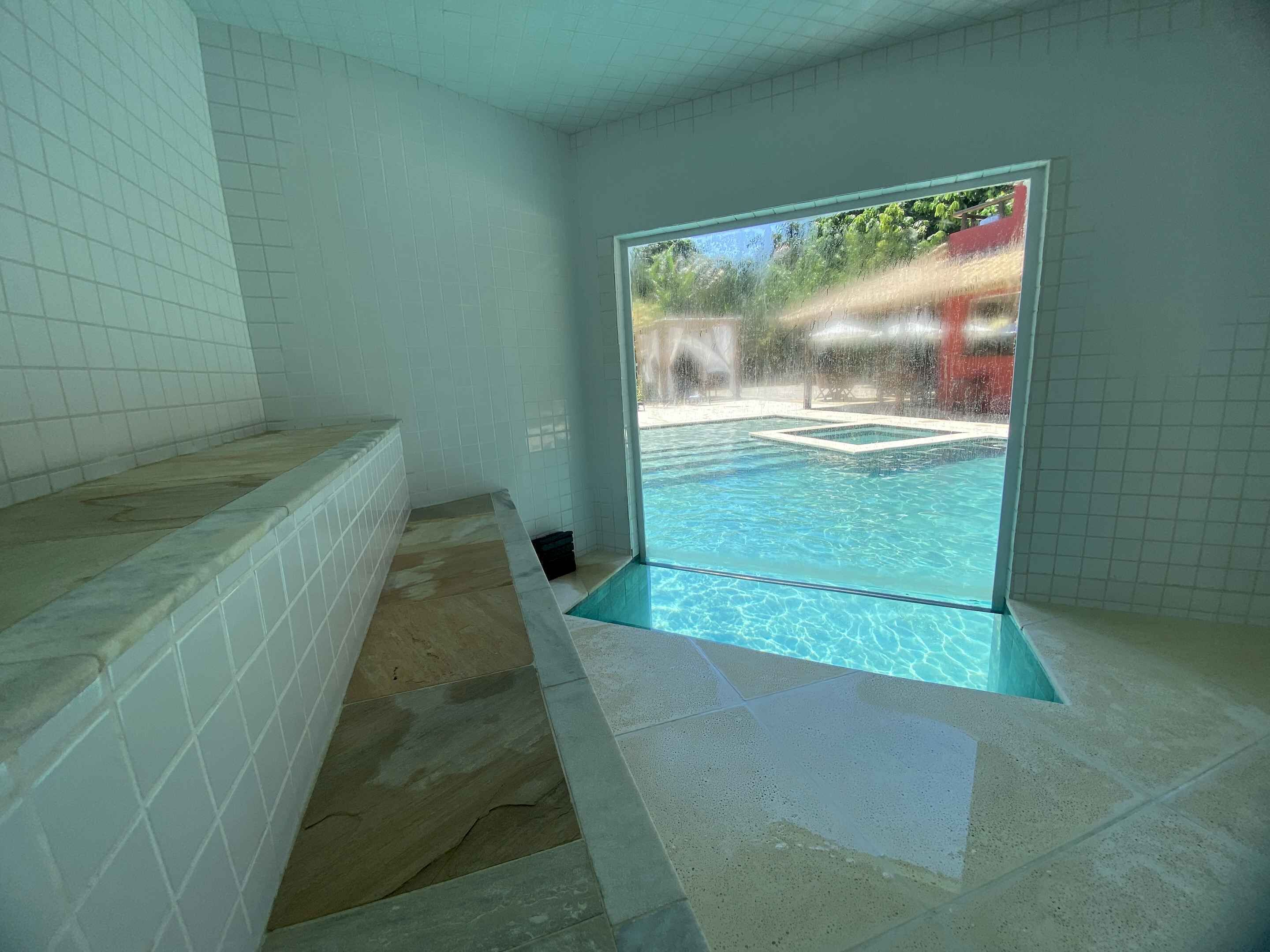A spa room with a view of an outdoor pool.
