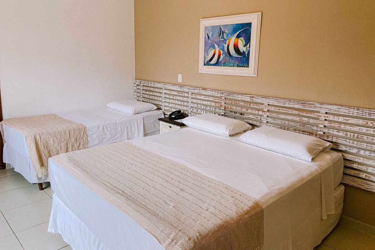 A hotel room with two beds, a nightstand, and a painting on the wall.
