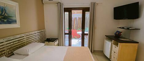 A hotel room with a bed, a desk with a chair, a television, and a view of the outside.