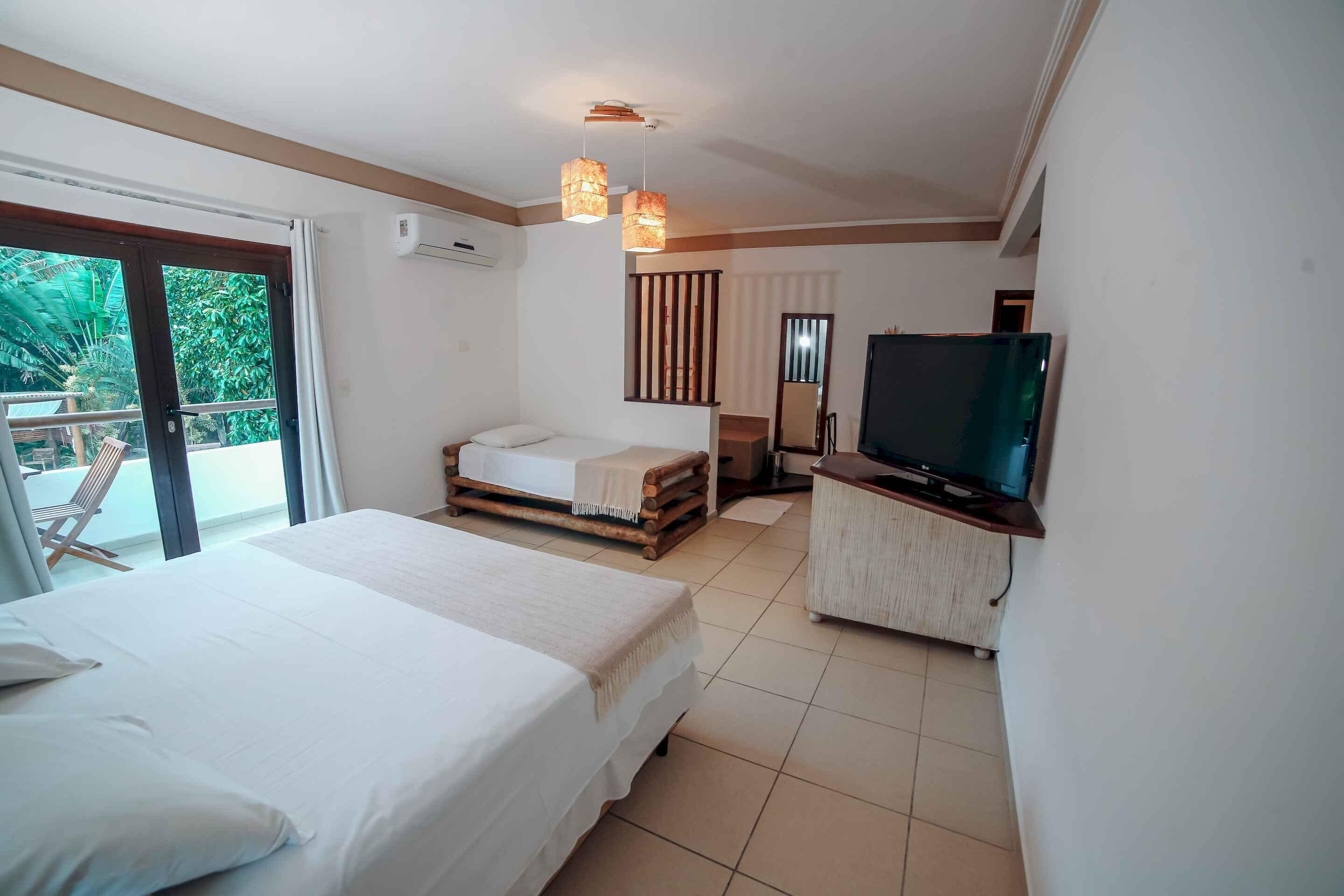 A hotel room with two beds, a TV, and a balcony with a chair.