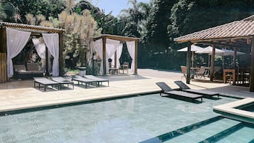 Relax by the serene pool surrounded by lush greenery and comfortable lounge chairs.