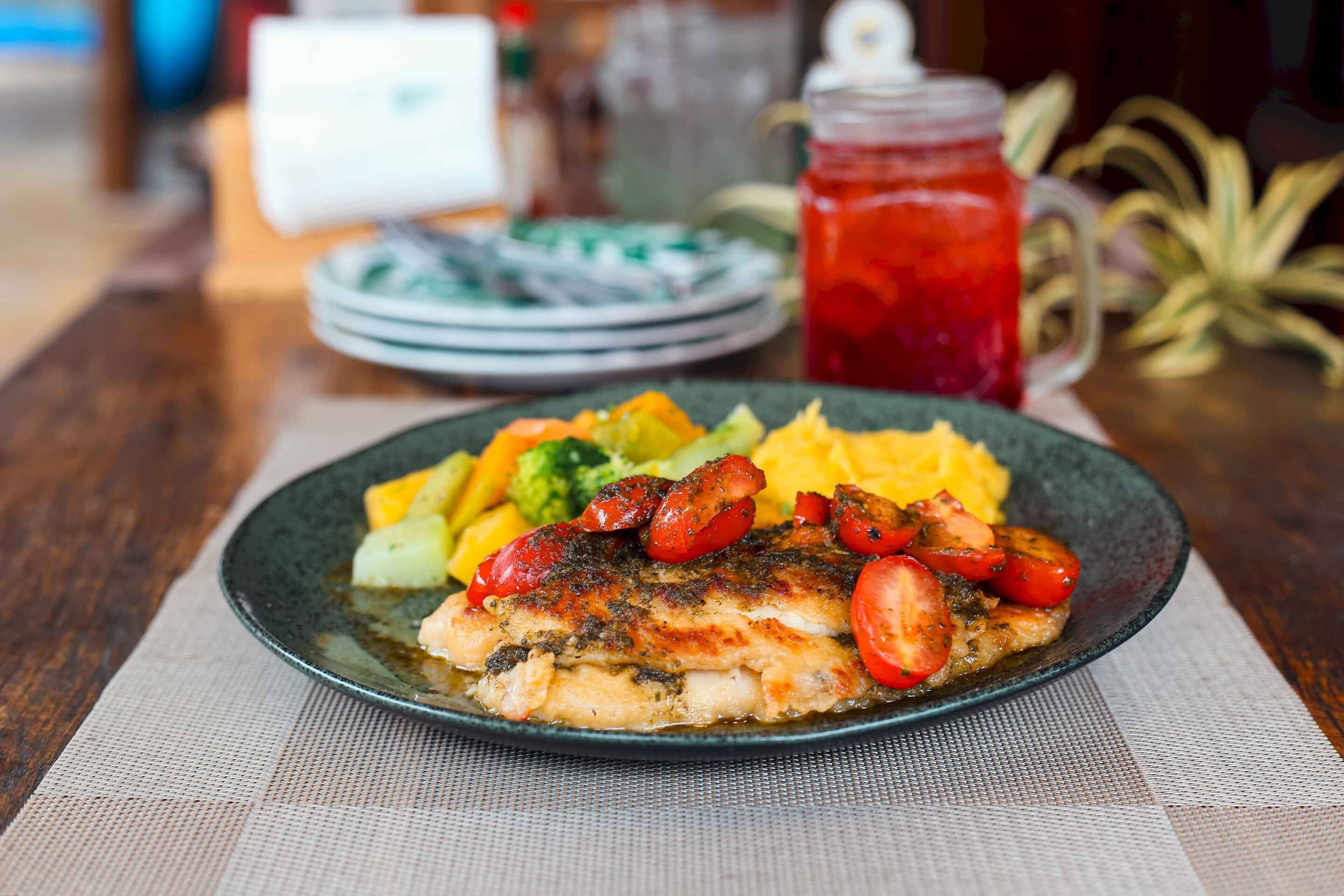Un plato de comida con un filete de pescado, verduras y puré de papas.