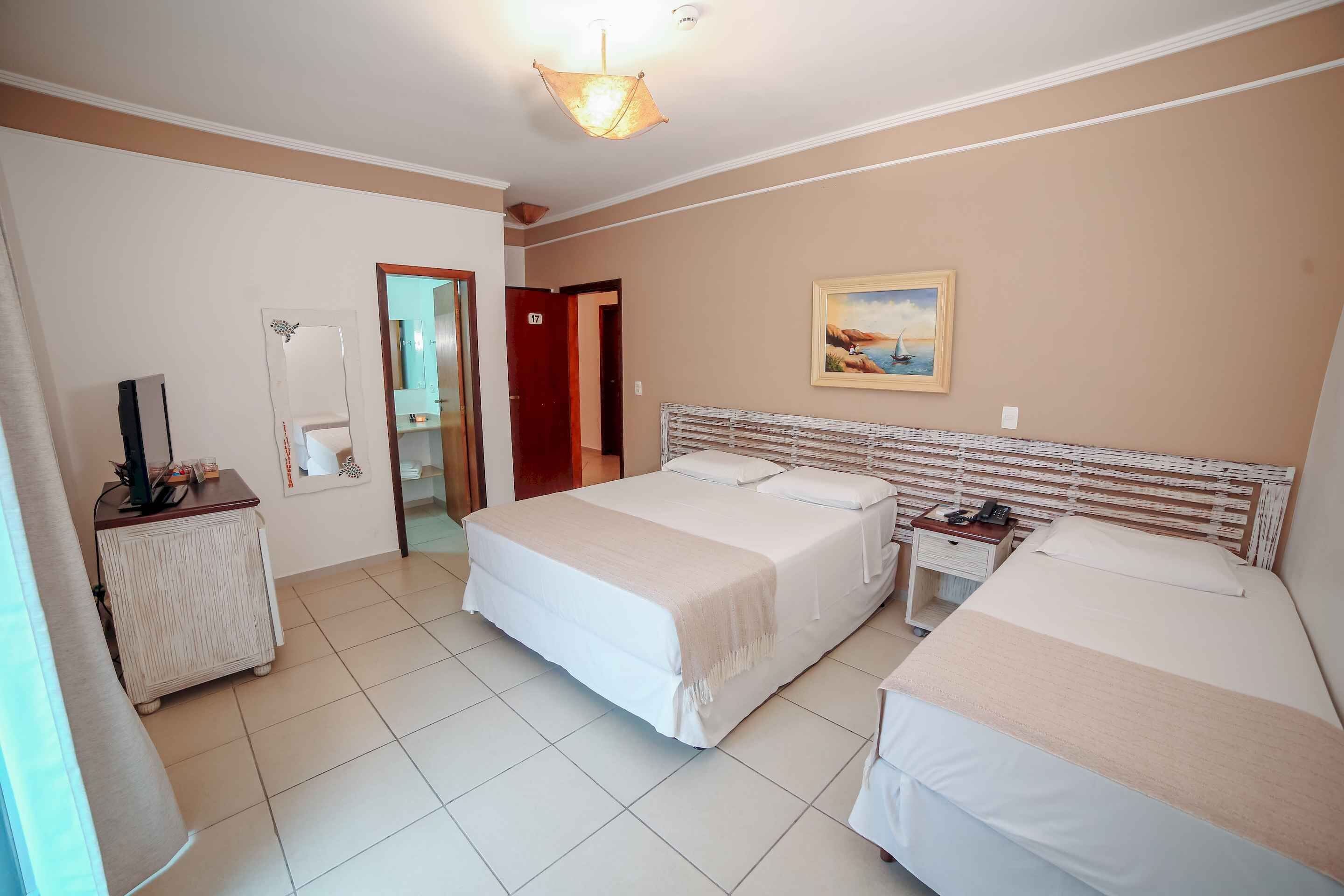 A hotel room with two beds, a desk, a chair, and a painting on the wall.