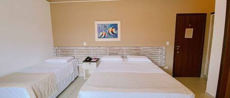 Habitación de hotel con dos camas, una mesita de noche, un cuadro en la pared y una puerta.