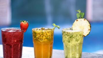 Drie glazen met verschillende gekleurde dranken, elk versierd met fruit of kruiden.