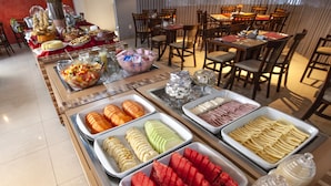 Un buffet proposant une variété de plats, notamment des fruits, des fromages et des viandes.