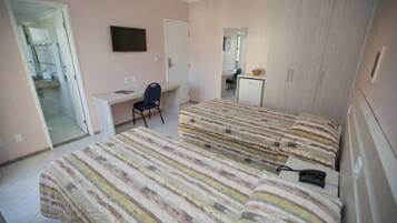 A bedroom with two beds, a desk, a chair, and a TV.
