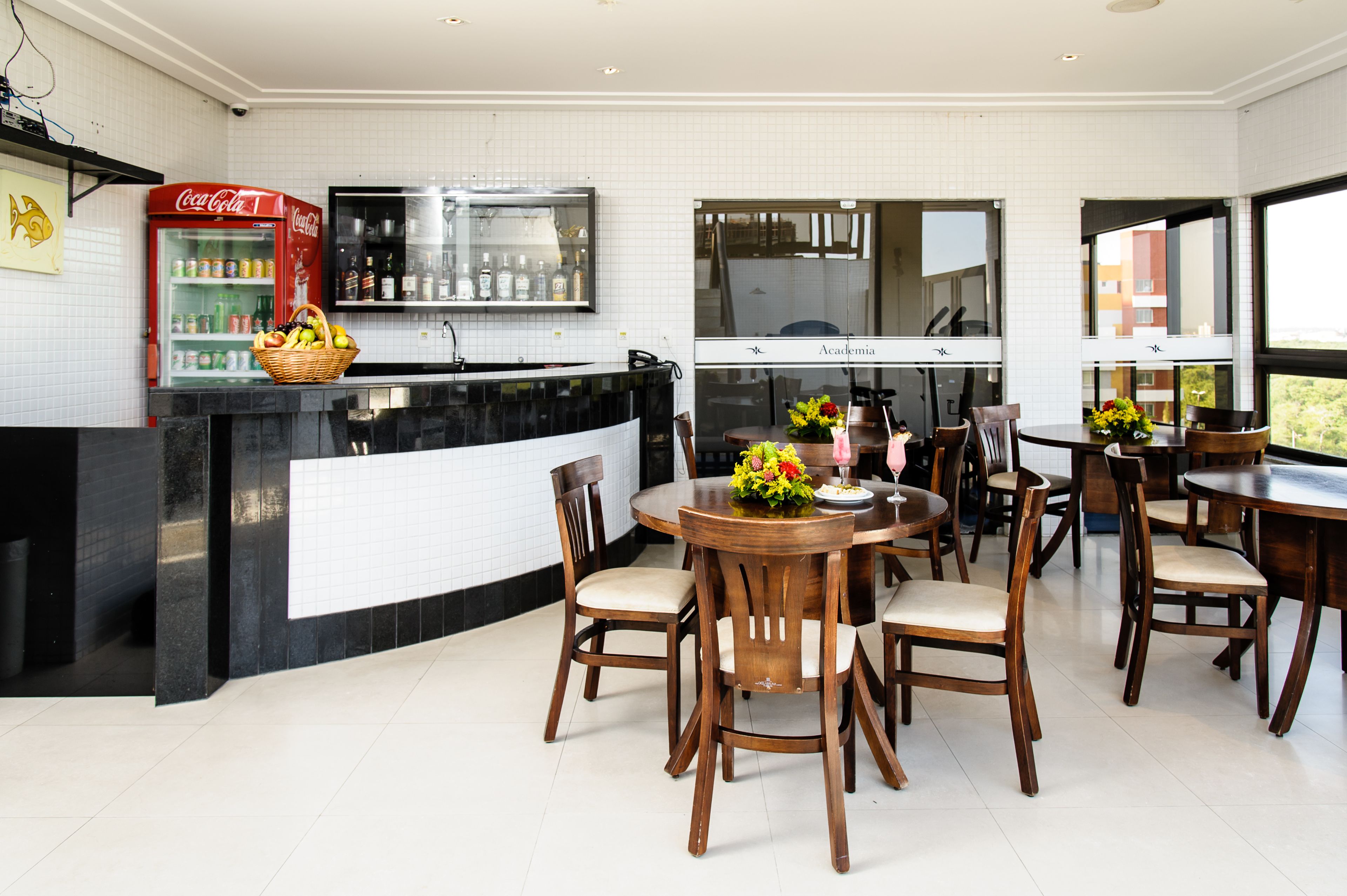 A modern kitchen with a black countertop, a red Coca-Cola refrigerator, and a dining area with wooden chairs and a round table.