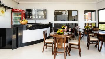A modern kitchen with a black countertop, a red Coca-Cola refrigerator, and a dining area with wooden chairs and a round table.