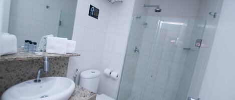 Un baño con lavamanos, inodoro y cabina de ducha de vidrio.