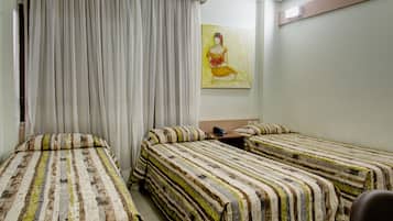 A hotel room with two beds, a painting on the wall, and a window with curtains.