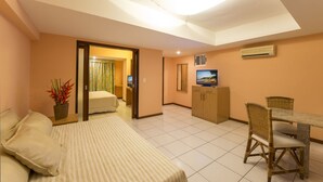 Una habitación de hotel con cama, escritorio con silla, televisión y pequeña zona de kitchenette.