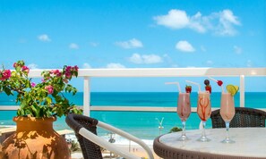 A table with drinks and a potted plant, overlooking a beach with a clear sky. - Vip Praia Hotel (Natal)