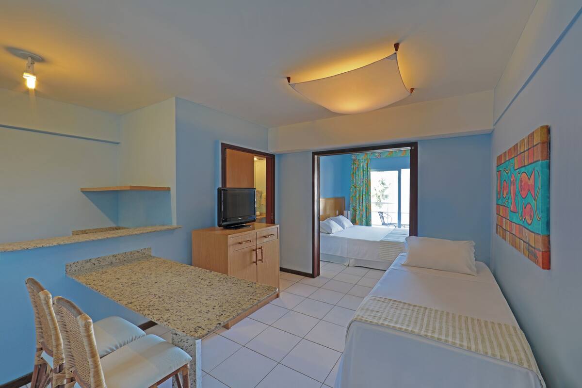 A hotel room with a bed, a TV, a small table, and a chair.