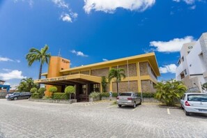 A hotel with a yellow facade, palm trees, and a clear blue sky. - Pizzato Praia Hotel (Natal)