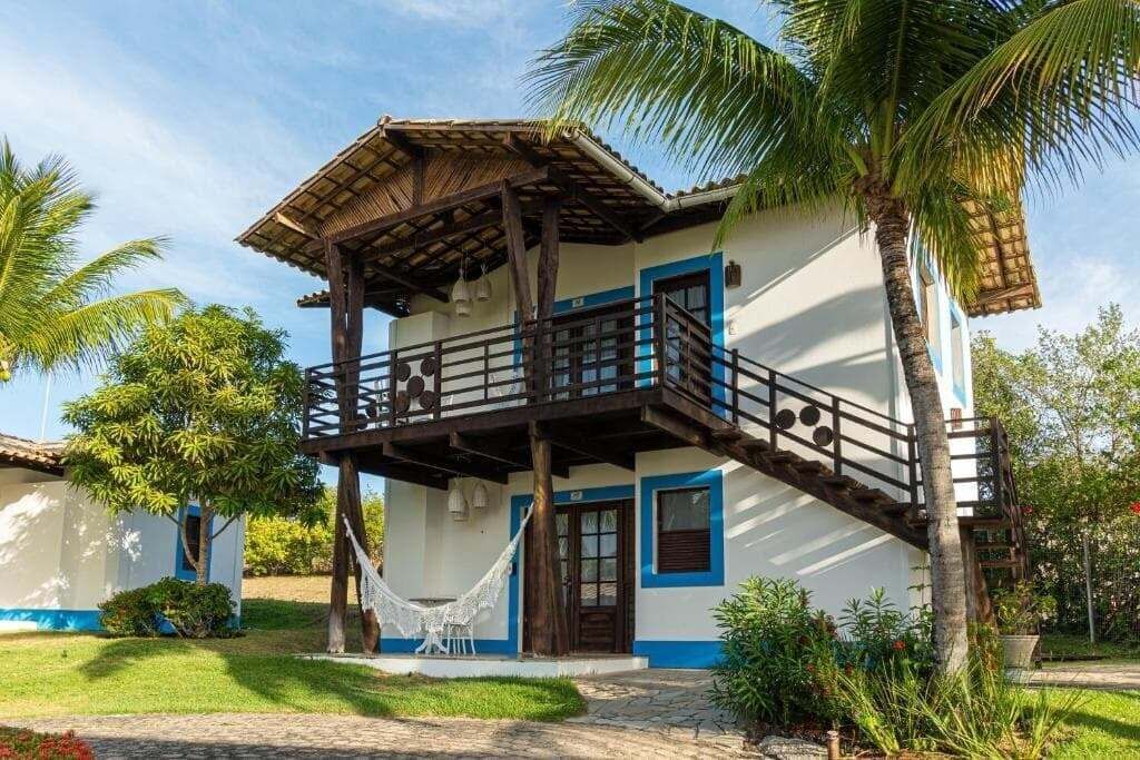 A two-story building with a balcony, a hammock, and a palm tree.