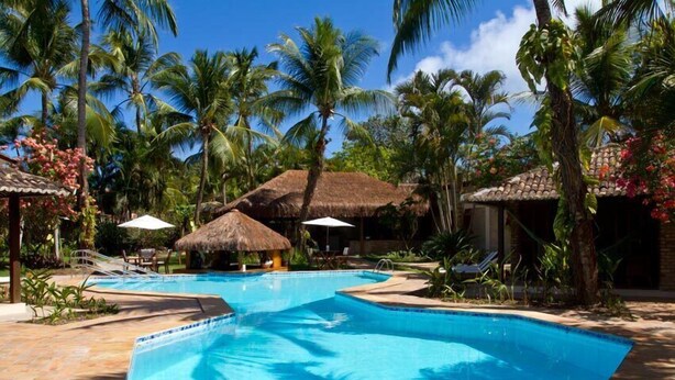 A pool area with multiple pools, palm trees, and thatched-roof structures. - Pousada Berro Do Jeguy (Tibau do Sul)