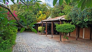 A cobblestone pathway leading to a covered outdoor area with a brick wall and greenery. - Pousada Berro Do Jeguy (Tibau do Sul)