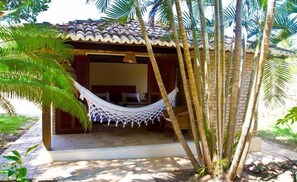 A small, single-room structure with a tiled roof, a hammock, and a bed. - Pousada Berro Do Jeguy (Tibau do Sul)