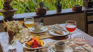 A table set for breakfast with a view of a pool and tropical plants. - Pousada Berro Do Jeguy (Tibau do Sul)