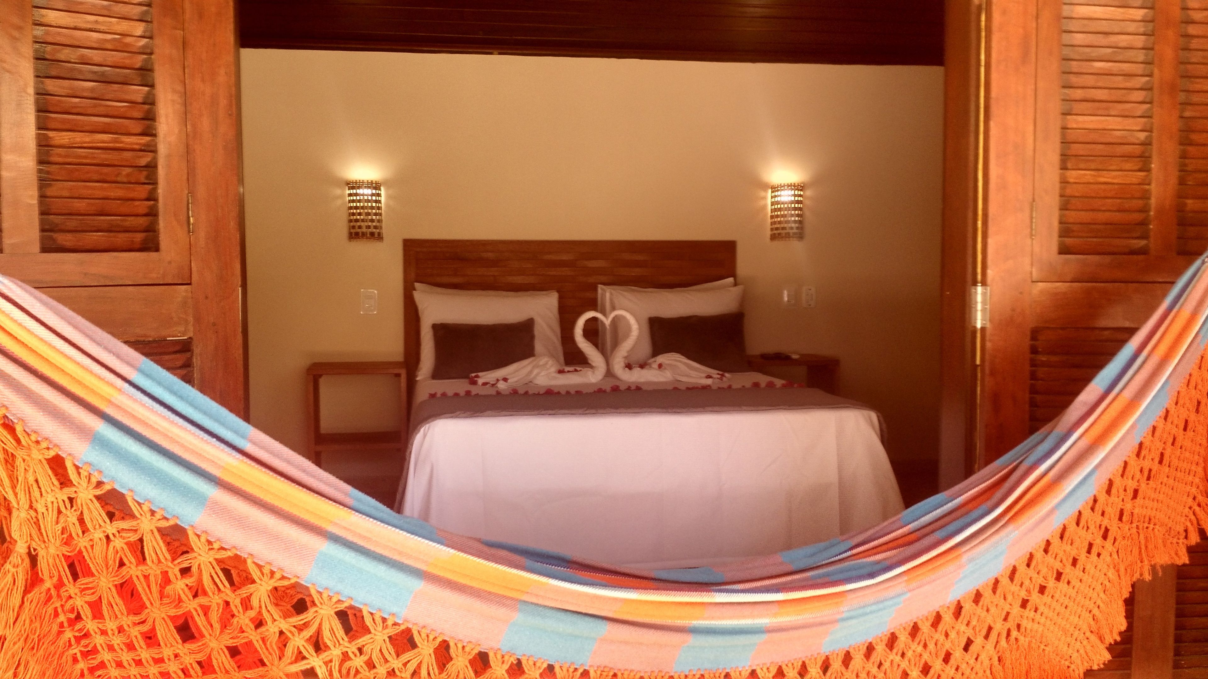 Una cama con una colcha con forma de corazón, dos luces fijadas a la pared y una hamaca.