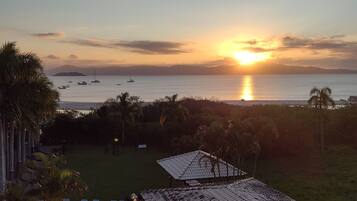 Un resort con piscina, sillas de descanso y vista al atardecer sobre el mar.