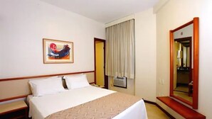 A hotel room with a bed, a bedside table, a mirror, and a window with curtains. - Hotel Boulevard Express (Belo Horizonte)