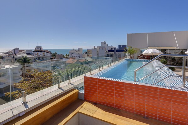 Une piscine sur le toit offrant une vue dégagée sur la mer et les bâtiments environnants.
