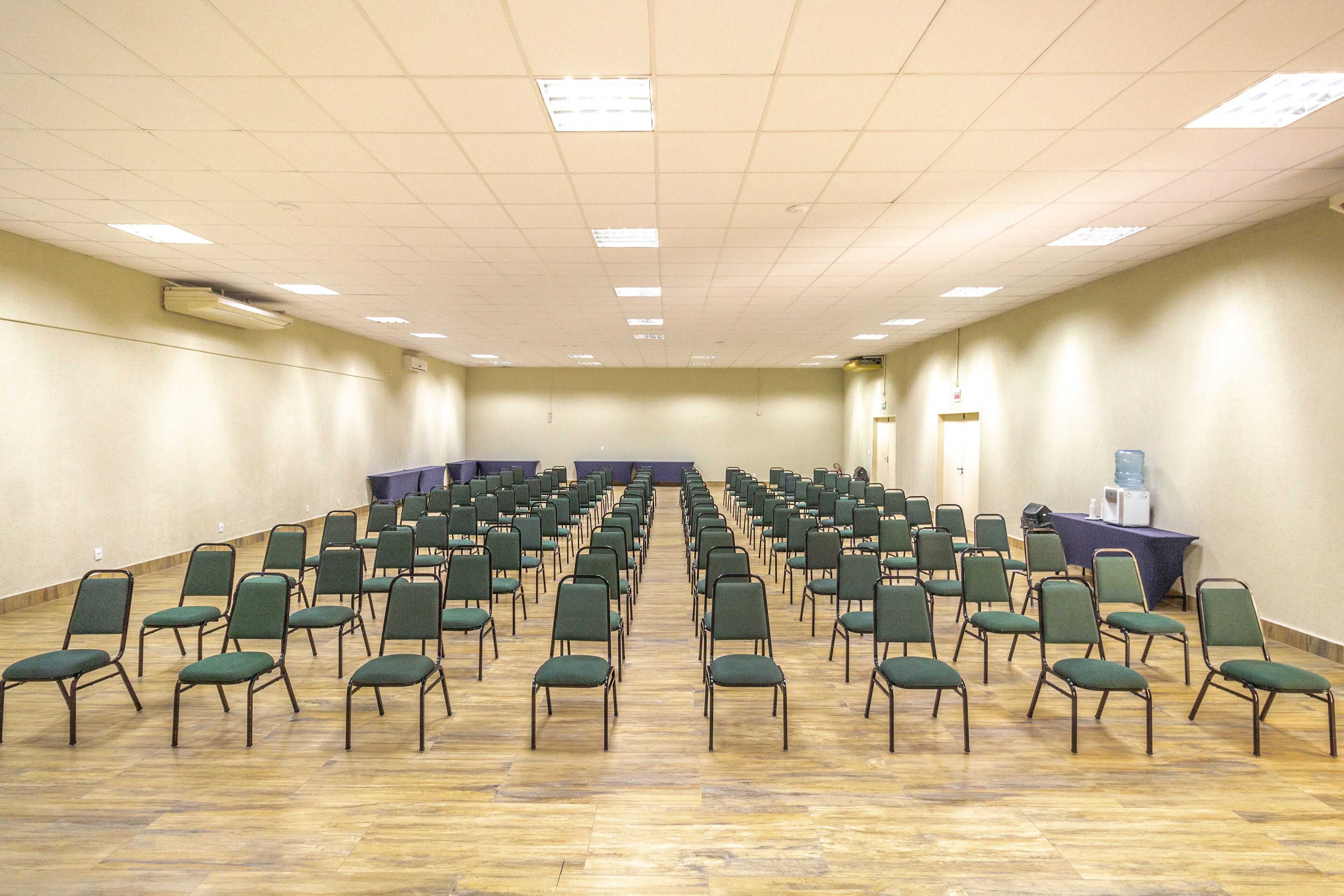 A conference room with rows of green chairs, a water cooler, and a table with a purple tablecloth.