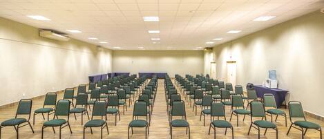 A conference room with rows of green chairs, a water cooler, and a table with a purple tablecloth.