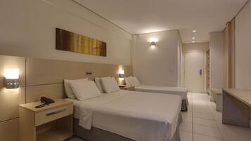 A hotel room with two beds, a bedside table with a phone, a nightstand, and a wall-mounted light fixture.