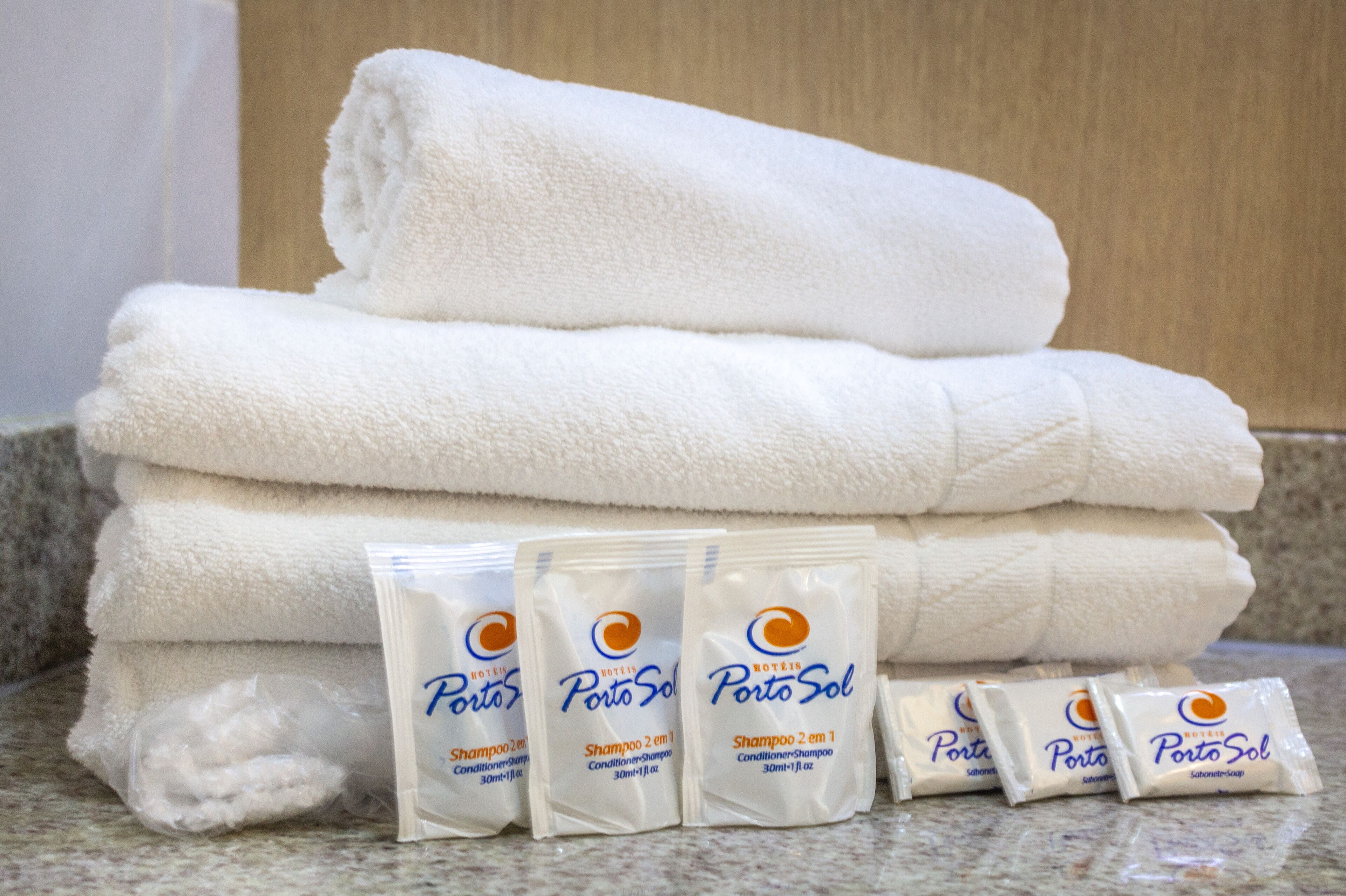 Une pile de serviettes blanches et plusieurs paquets de shampoing Porto Sol.