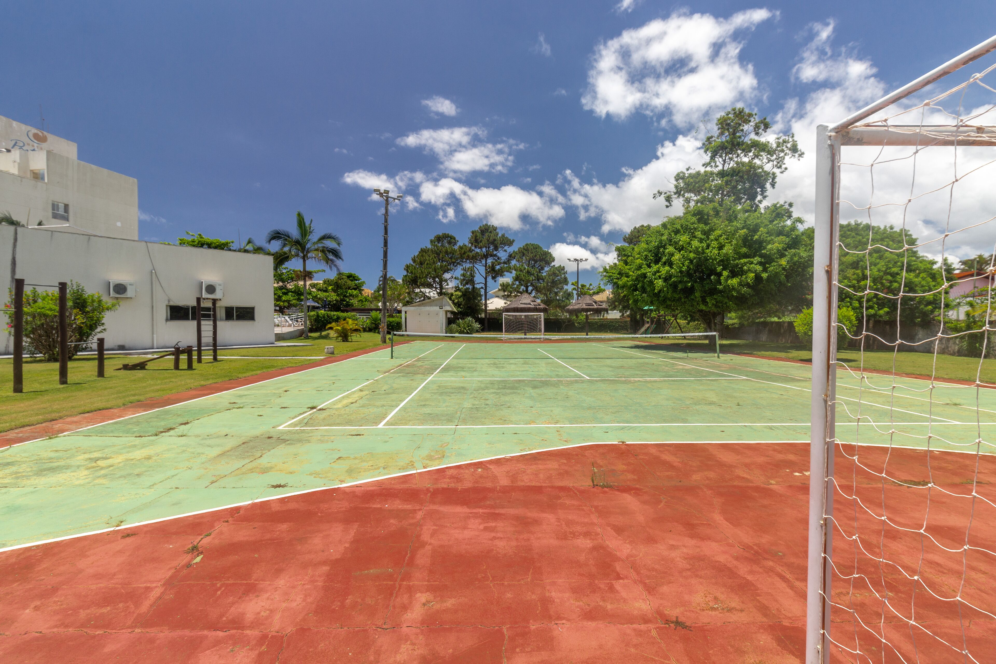 Un court de tennis avec un filet, entouré de bâtiments et d’arbres.