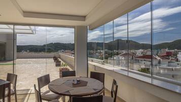Uma área de refeições moderna com uma grande janela de vidro que oferece vista para a cidade e colinas.