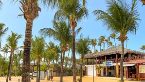 A beachside area with palm trees, a thatched-roof building, and a sign for 'Pousada Nola'. - Rede Andrade Pousada do Norte (Jijoca de Jericoacoara)