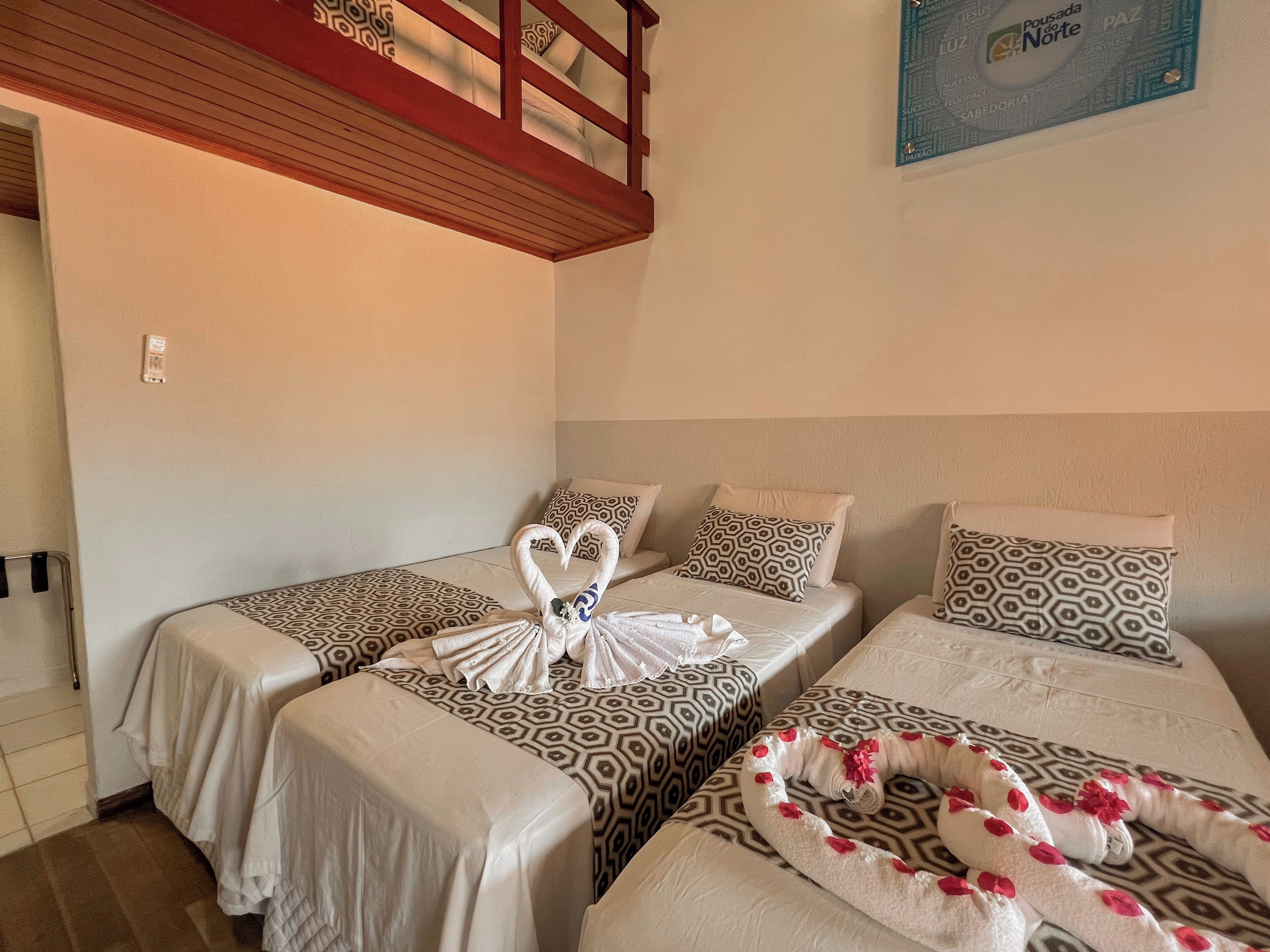 A hotel room with two single beds, each with patterned bedding and pillows. There is a wooden headboard and a wall-mounted artwork.