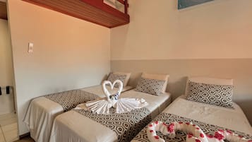 A hotel room with two single beds, each with patterned bedding and pillows. There is a wooden headboard and a wall-mounted artwork.