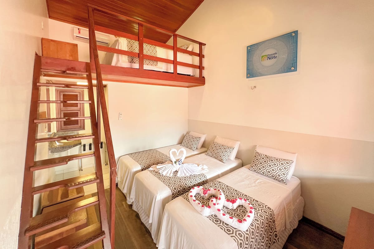 Una habitació amb lliteres, una escala de fusta i un aire condicionat fixat a la paret.
