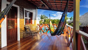 A wooden deck with a hammock, a wicker chair, and a pool view. - Rede Andrade Pousada do Norte (Jijoca de Jericoacoara)