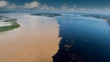 An aerial view of a coastal area with a large body of water, a sandy beach, and a green vegetated area.