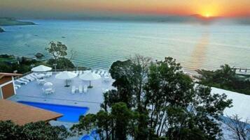 Una piscina al aire libre, sombrillas, sillones reclinables de piscina