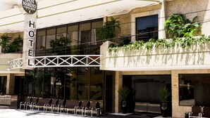 A hotel with a prominent 'HOTEL' sign, outdoor seating, and a balcony with plants. - San Marino Cassino Hotel (Balneário Camboriú)