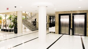 A modern lobby with a central column, a staircase, and two elevators. - San Marino Cassino Hotel (Balneário Camboriú)
