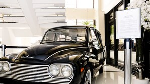 A classic black car with chrome detailing, parked indoors with a modern interior and a sign about the car's history. - San Marino Cassino Hotel (Balneário Camboriú)