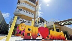 A building with multiple balconies and a large sun in the sky. - Jatobá Praia Hotel (Aracaju)