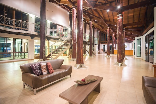 A spacious lobby with a brown leather sofa, a wooden coffee table, and a staircase with a glass railing. - Wetiga Hotel (Bonito)