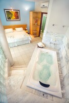 Habitación de hotel con cama, vestidor, baño con bañera y zona de ducha.
